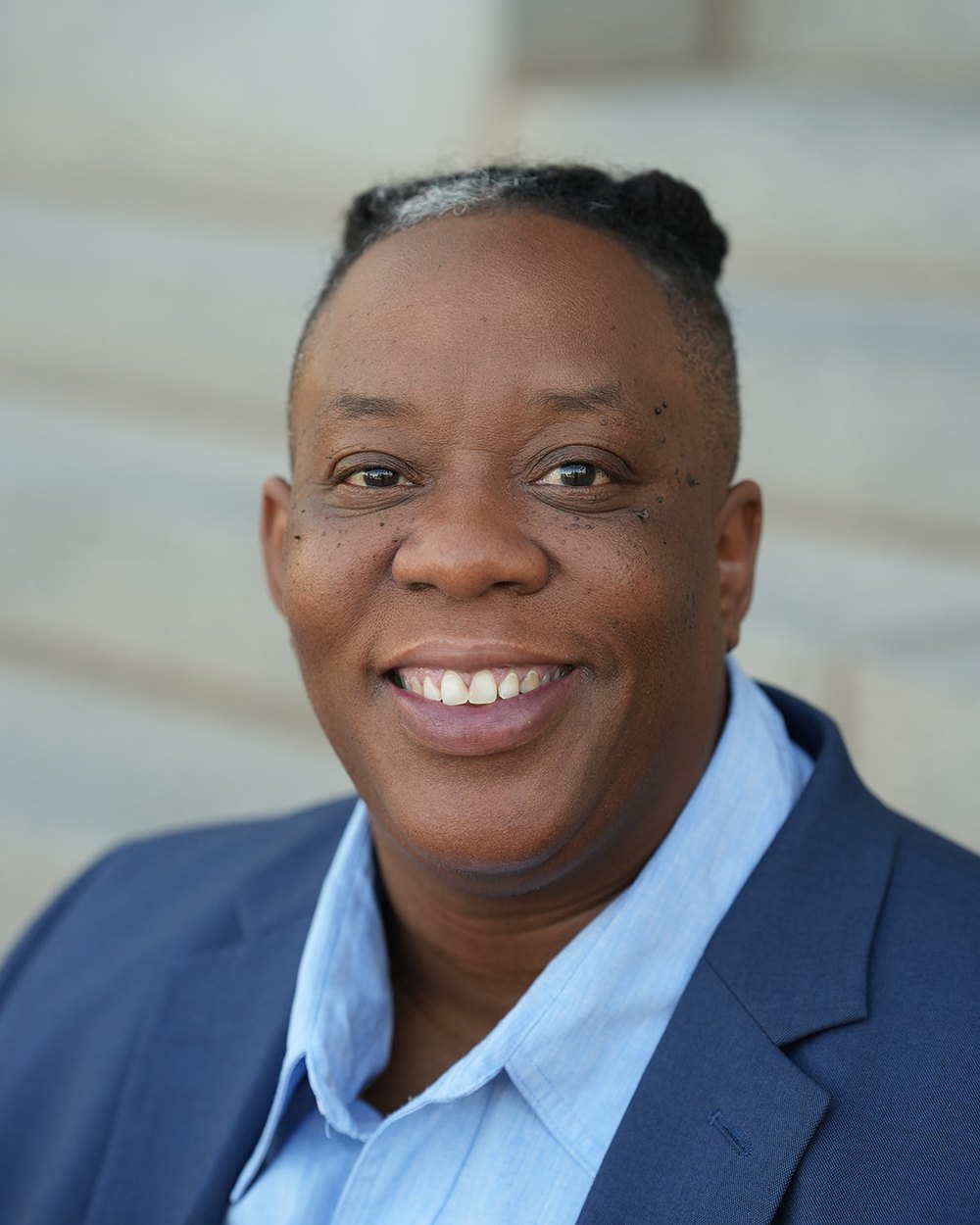 Dana Johnson, smiling, wearing a navy blazer over a light blue shirt.